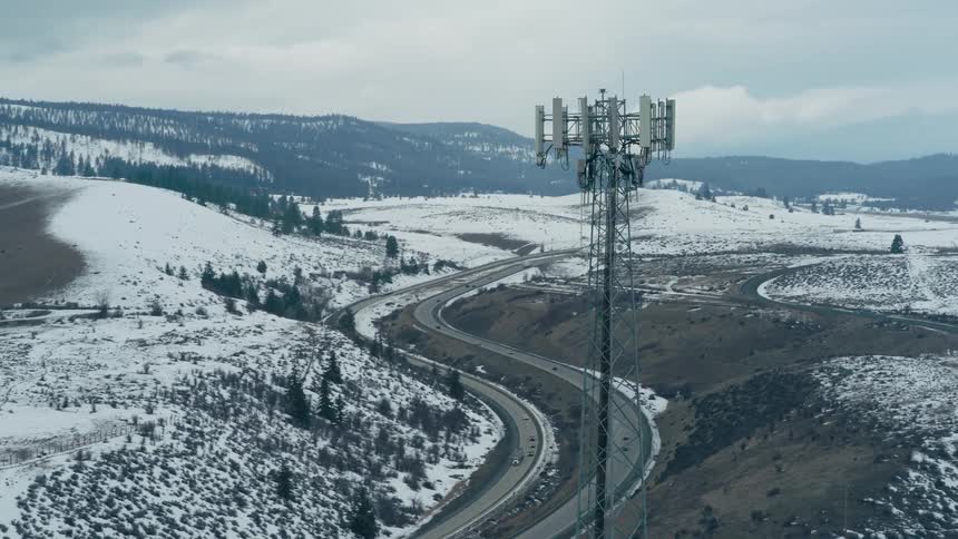 Rising orbit around a 5G network tower alongside a winding interstate highway