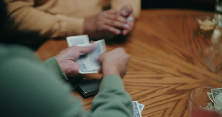 Pair of hands dealing cards from a deck on the table