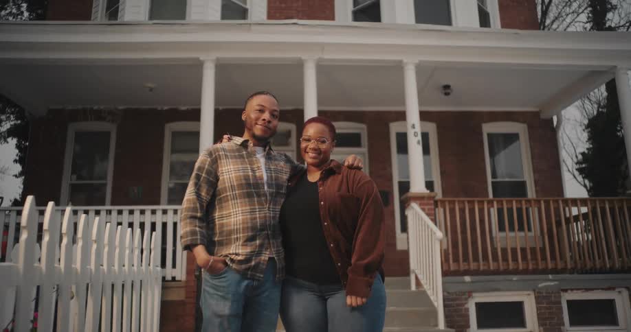 Man and woman happily hugging each other while standing in front of a house