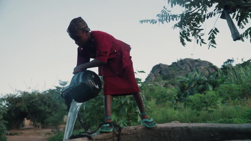 Girl drawing water from a well