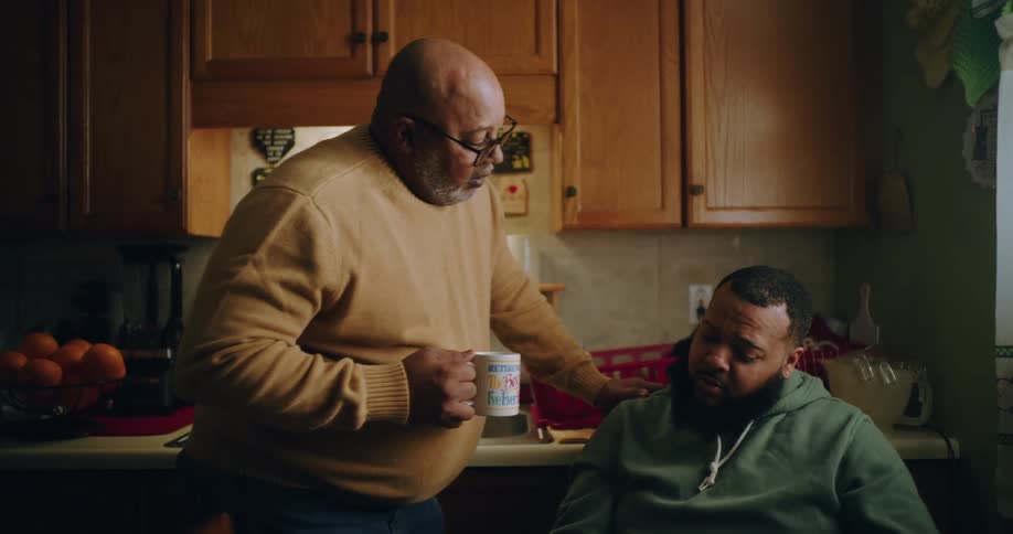 Father talking to adult son in kitchen