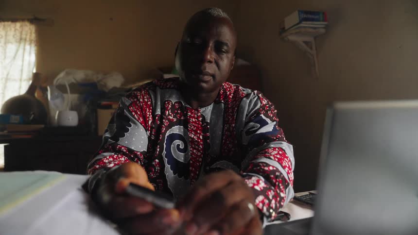 Man sitting at a table picking up a cell phone and removing the usb cable