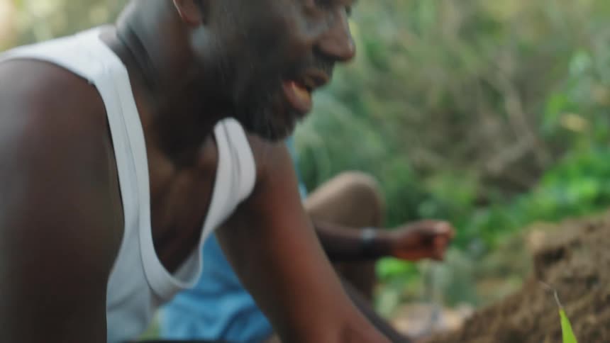 Man putting soil and fertilizing a plant inside a plastic bag