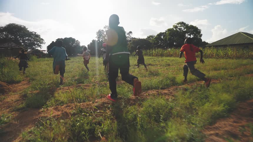 Group of small children running on the grass of a field