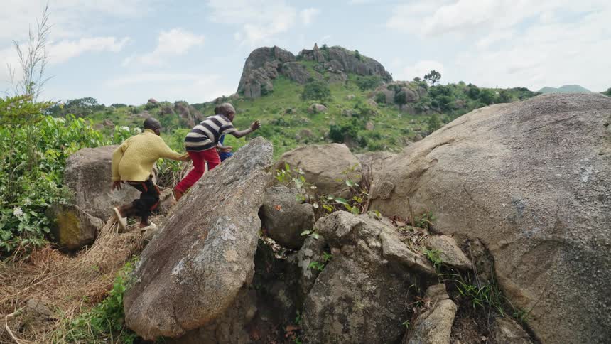 Children run and jump over the boulders