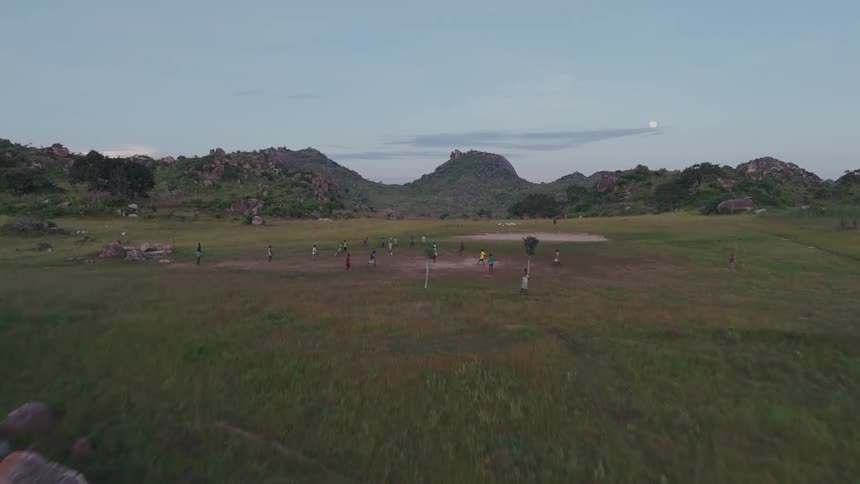 Aerial panorama of an agricultural environment and in the background children playing soccer