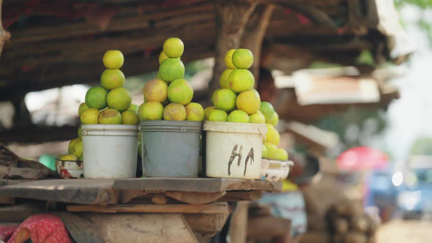Limes stacked up in buckets on display at an outdoor market