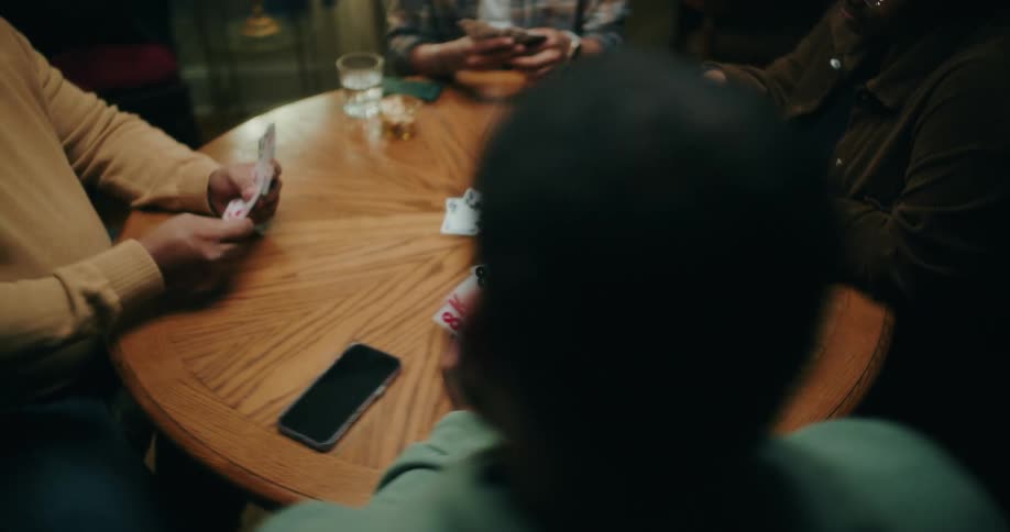 Freinds gathered at a round table playing cards
