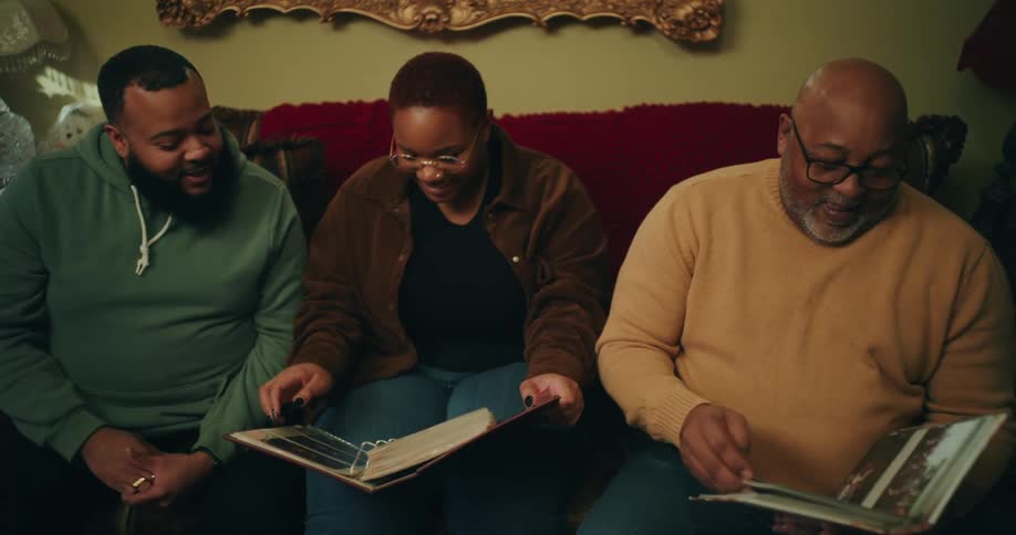 Family laughs and talks while looking through photo albums in their living room