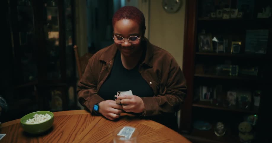 The group of people sitting around a round table who are happily chatting while playing a game of cards