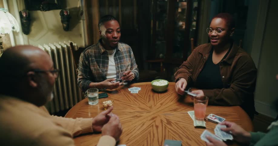 A group of friends or family plays cards and has fun in a cozy room at home