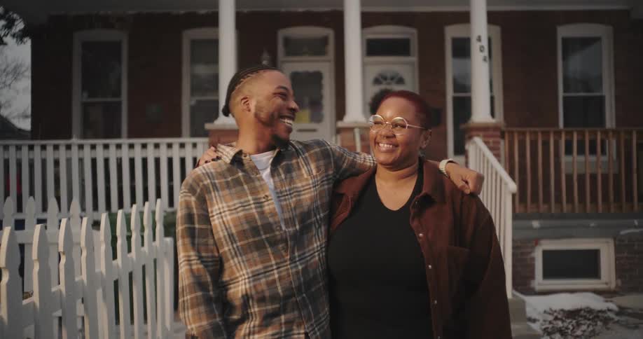 A man and woman are laughing in front of the home
