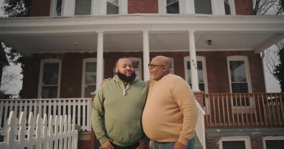 A father and son hug in front of the home