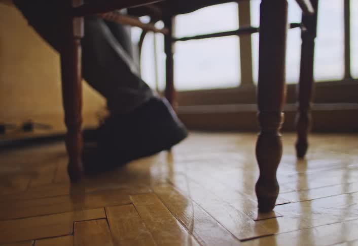Person walks to a chair sits down and pulls the chair closer to the wall