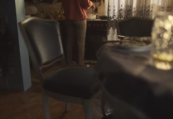 Rushing youth grabs his backpack while his mother cooks in the kitchen