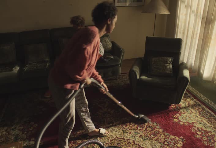 A mother is vacuuming the living room