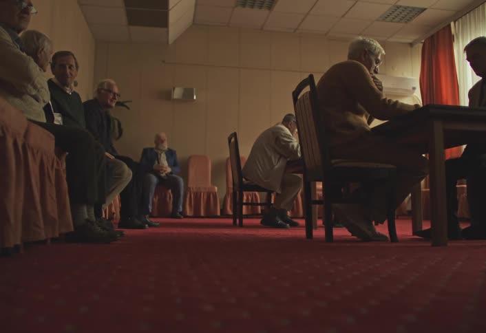 Group of men sitting on chairs playing and watching chess