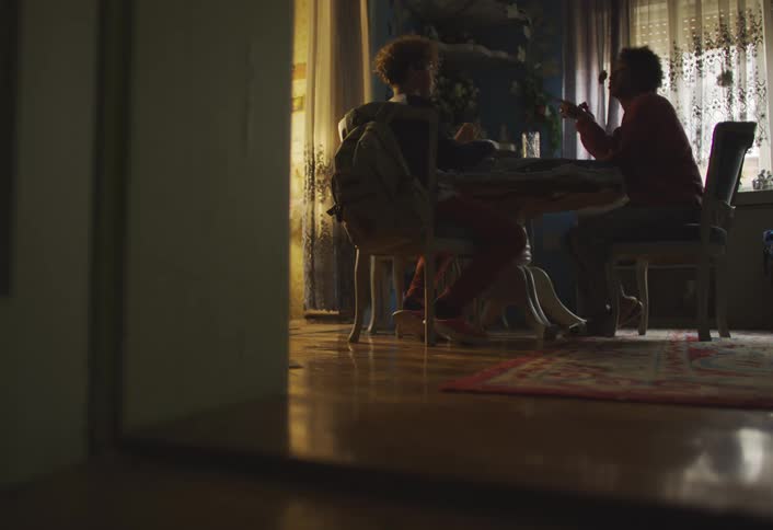 Mother and son sitting at a table talking and eating
