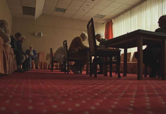Group of men watching and playing chess in a room