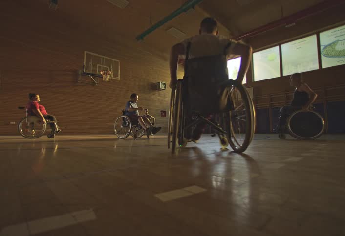 Players in wheelchairs pass the ball around the basketball court