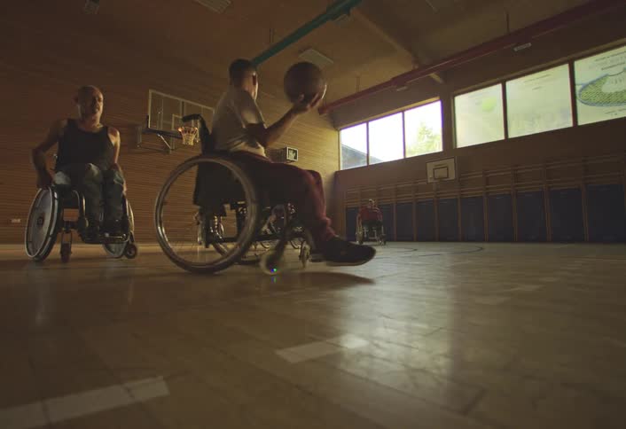 Wheelchair users training basketball indoors on a court