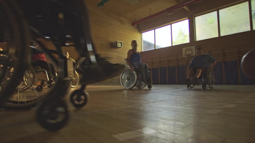 People in wheelchairs playing basketball on an indoor court