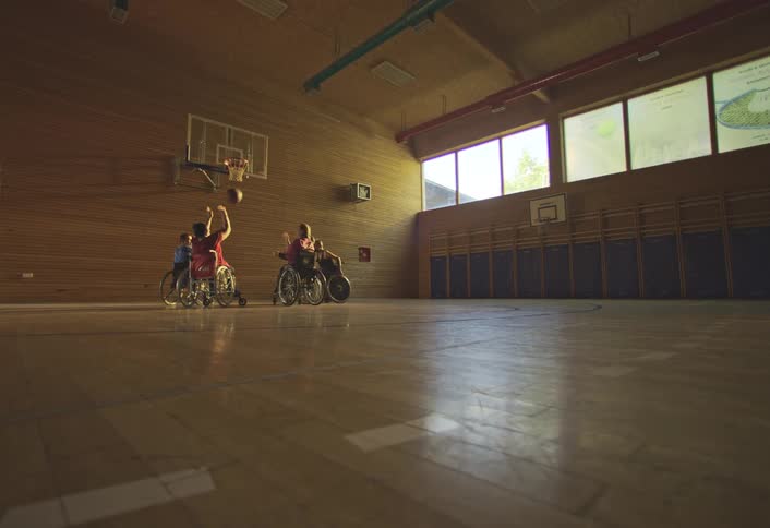 A person shoots the basketball from a wheelchair and scores