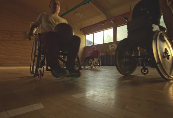 Group of wheelchair users running across a basketball court