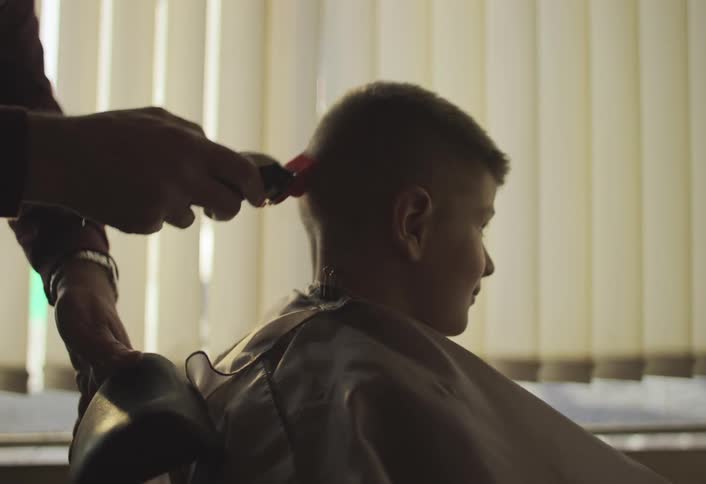 A boy smiles while getting a haircut