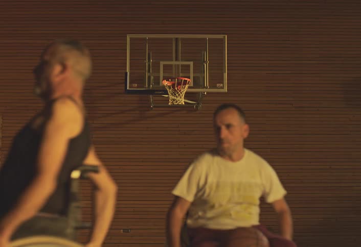 Men and women in wheelchairs running across a basketball court