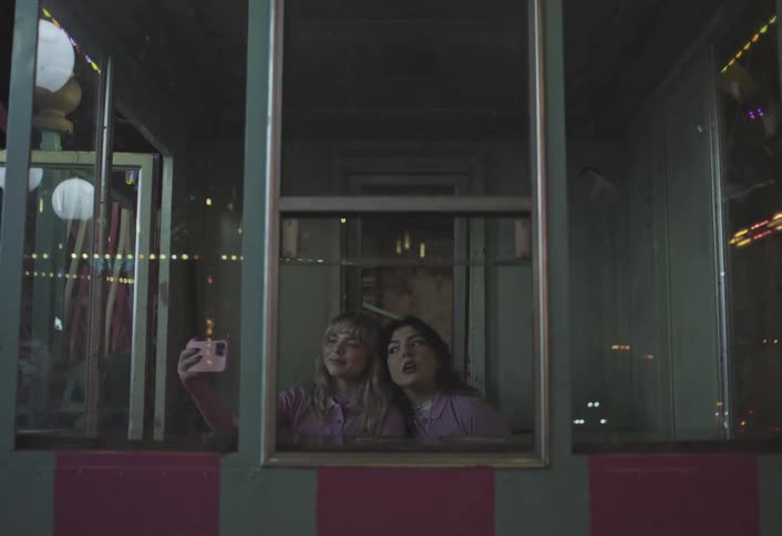Two girls are taking a selfie with their cell phone behind the window