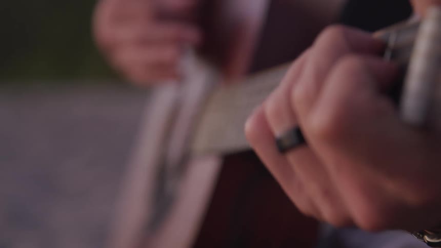 A man is playing his guitar outside
