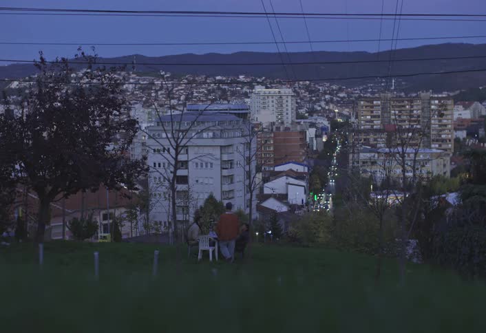 People sit at a table on a hill by the city