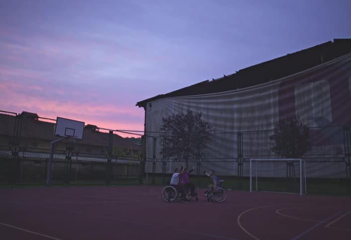 A man rides over on his wheelchair to high five other players on the court
