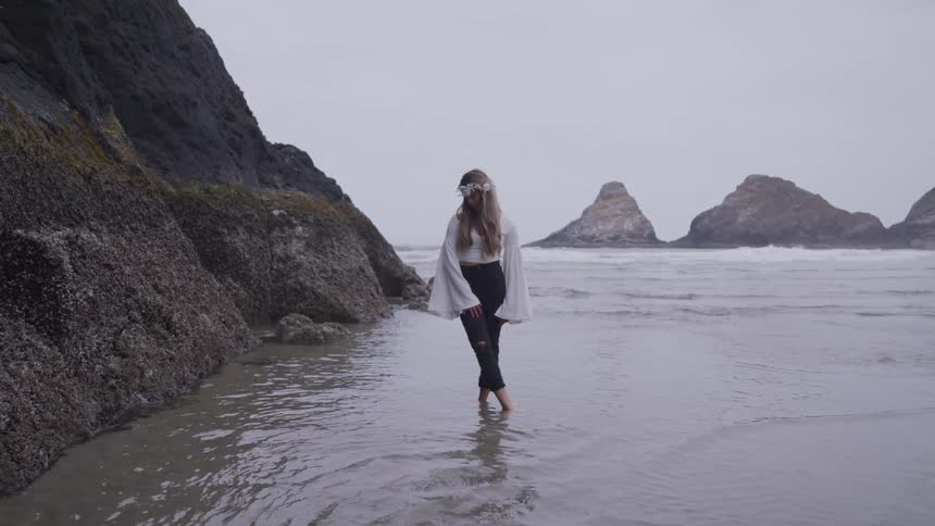 A woman is on the beach with her feet in the water