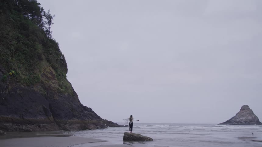 A woman has her arms out on the beach