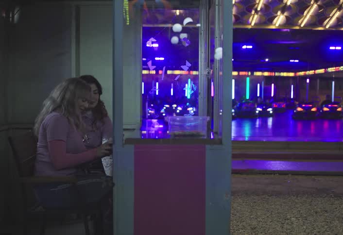 Teenage employees take a selfie while people are riding in the bumper cars at the carnival