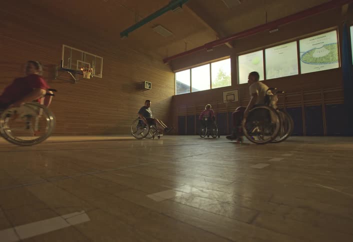 Wheelchair users playing basketball on a court during the day
