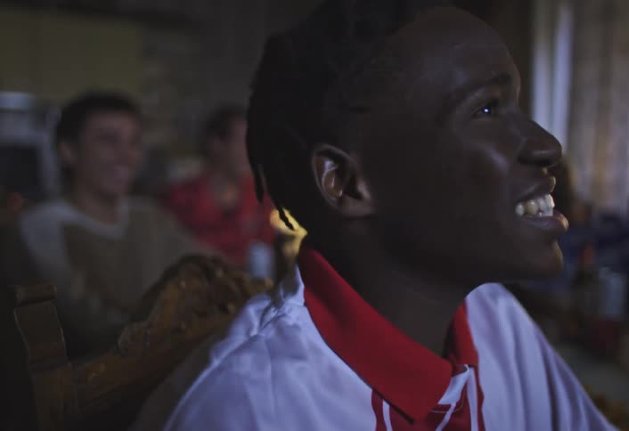 Portrait of a happy young man talking with his friends at the table while watching something