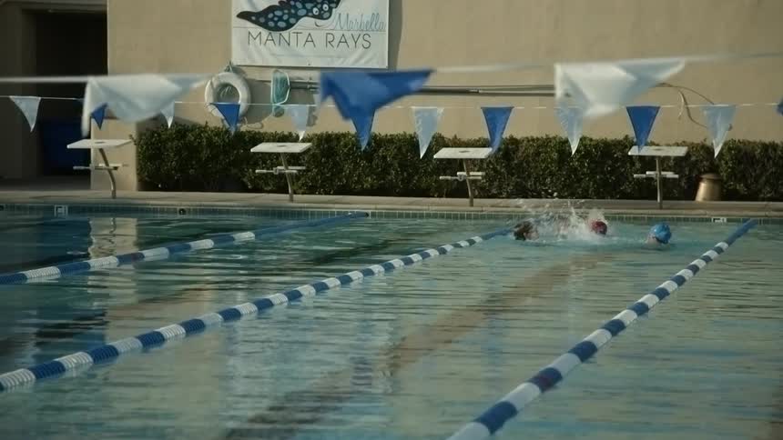 Four kids playing and splashing in a swim lane at a pool