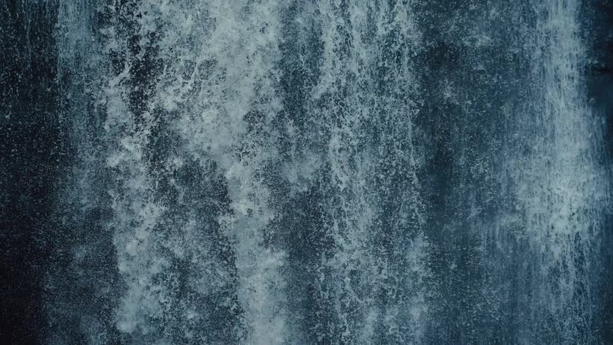 Closeup of a tall waterfall pouring into the creek below it
