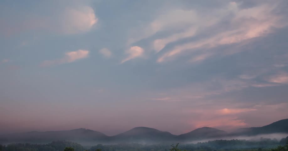 A pastel sky transitions to reveal a sprawling farmland in a mountain valley with distant peaks and soft clouds overhead
