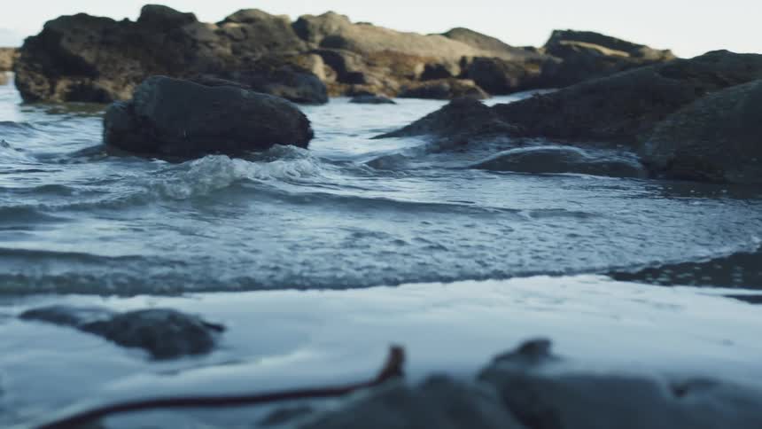 Water rushes into a low shoreline around the coastal rocks