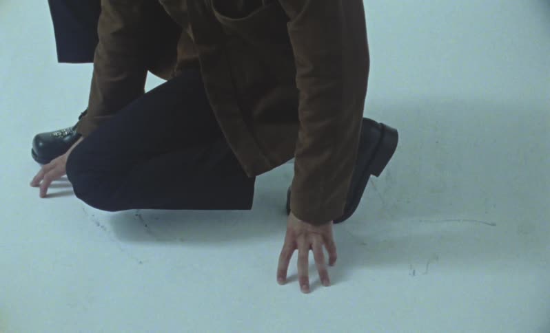 A person kneels on a white studio floor during a photo shoot momentarily illuminated by a camera flash