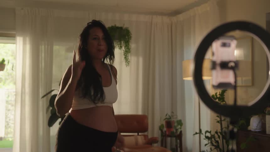 Pregnant woman dancing in front of a smartphone on a tripod