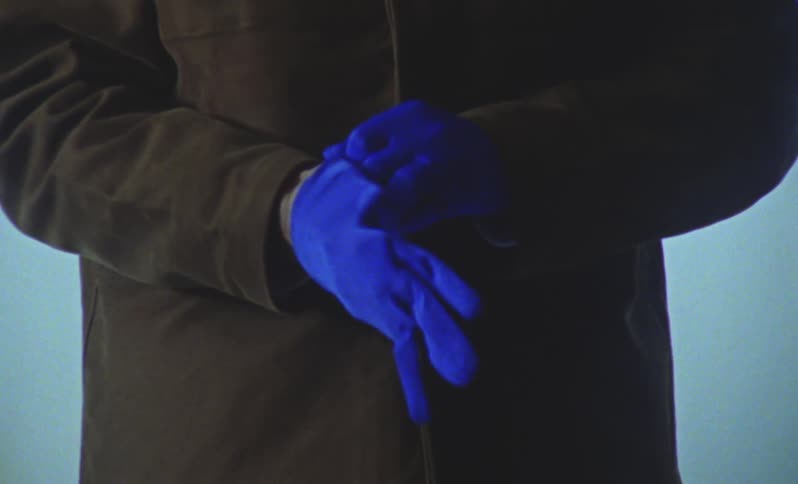 A man puts on a pair of blue gloves