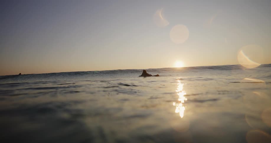 People float around on their surfboards at sunrise