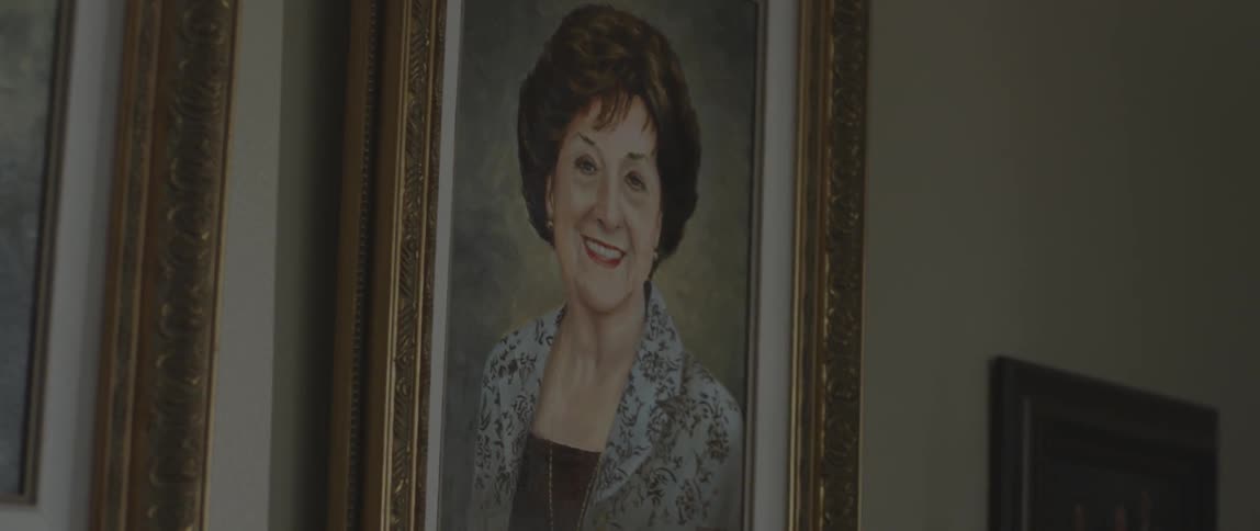 A portrait painting of a woman hangs on the wall