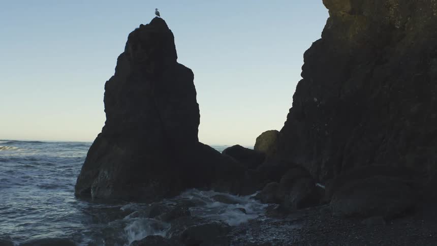 Waves roll into a rocky ocean coastline at sunrise