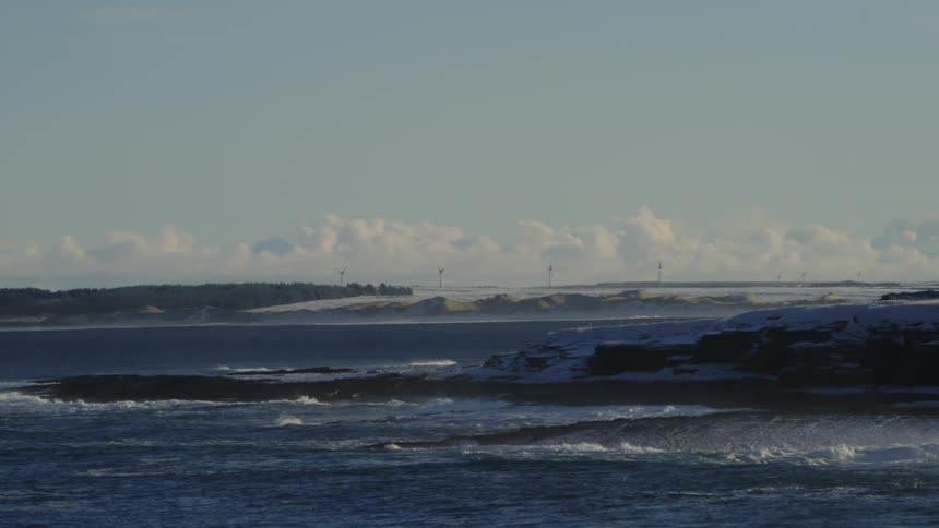 Landscape of choppy waters in an ocean with a snowy coastline